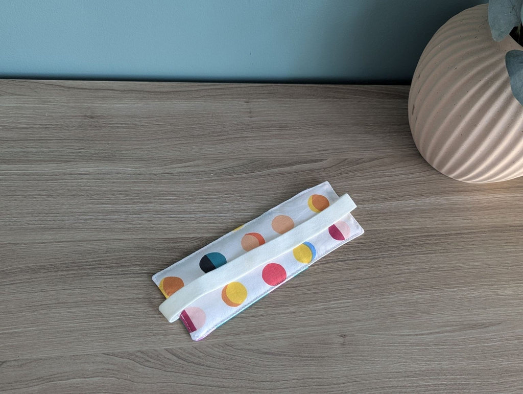A colorful polka dot cloth is placed on a wooden surface next to a vase.