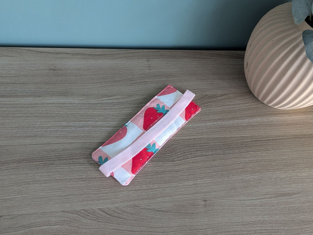 A pink and white striped object, possibly a bag or wallet, is placed on a wooden surface next to a vase.