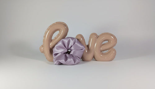 a pink balloon spelling out the word "LOVE" with a purple scrunchie on the left side.