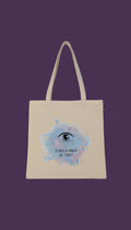 A beige tote bag with a printed design on it, featuring an eye and the text "JE PARLE LA LANGUE DES ETOLLES" (The language of the eye).