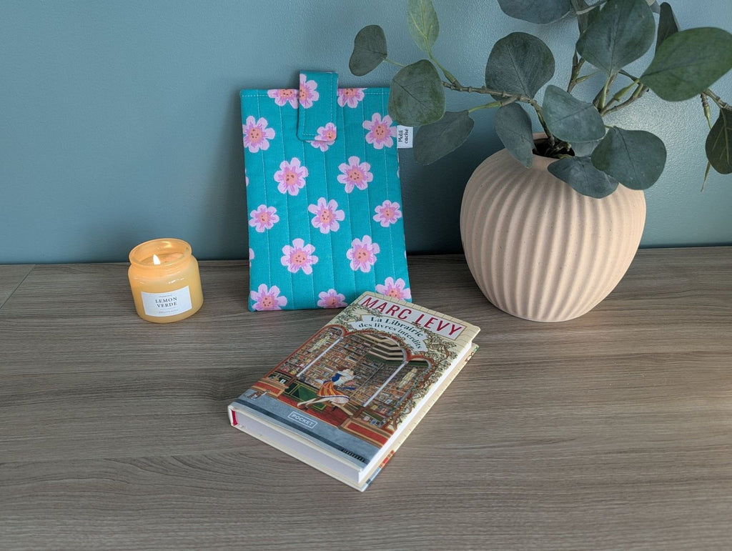 a wooden table with a book, a candle, and a vase with a plant.