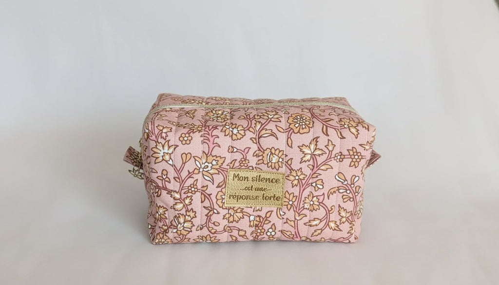 A pink and gold floral patterned bag with a gold label that says "Silence is golden".