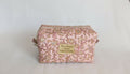 A pink and gold floral patterned bag with a gold label that says "Silence is golden".