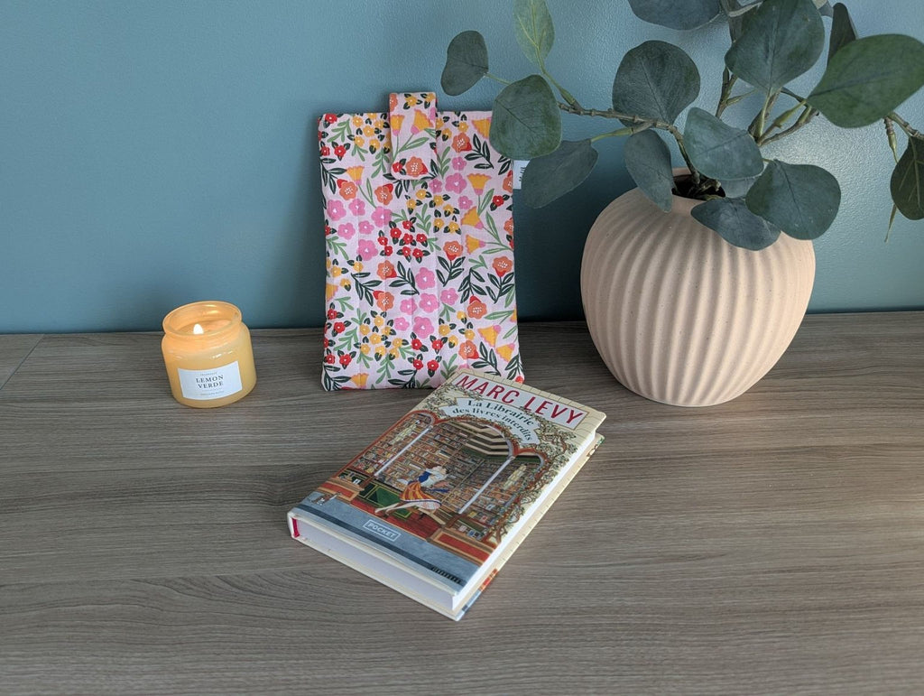 a wooden table with a book, a candle, and a vase with a plant.
