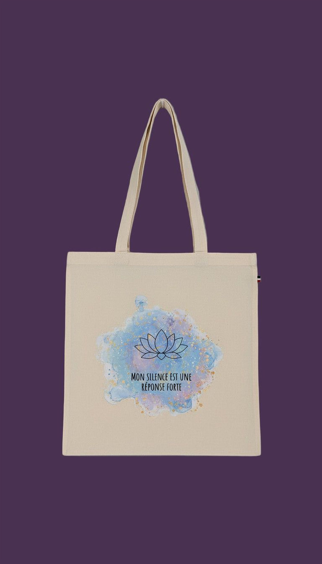 A beige tote bag with a blue and white watercolor design featuring a lotus flower and the text "MON SILENCE EST UMI RESPOSE FORTE" printed on it.