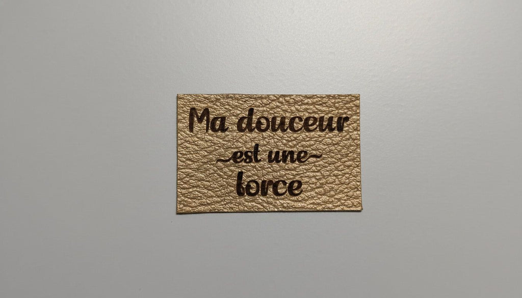 a rectangular piece of leather with the text "Ma ducer est une force" printed on it.