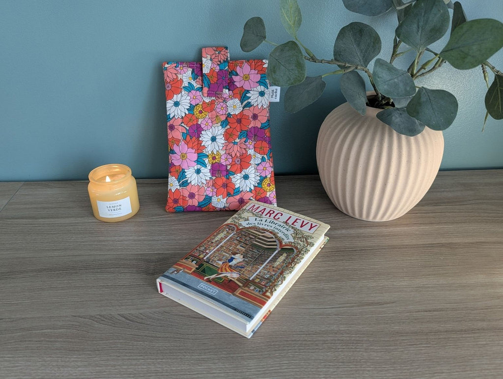 a wooden table with a book, a candle, and a floral bag.
