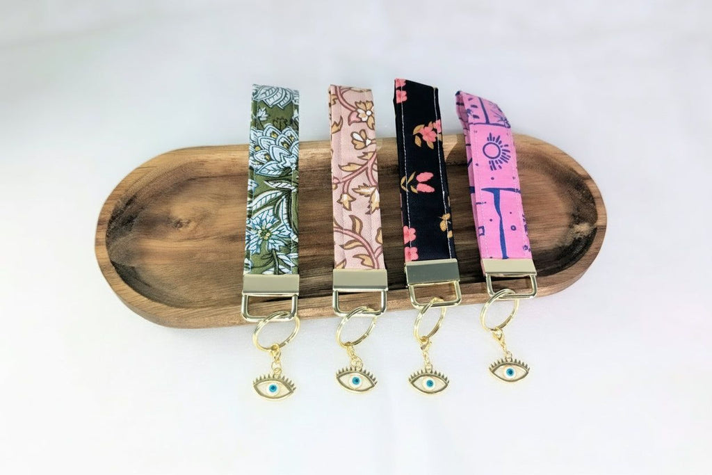 A wooden tray displaying four colorful keychains with eye-shaped charms hanging from them.