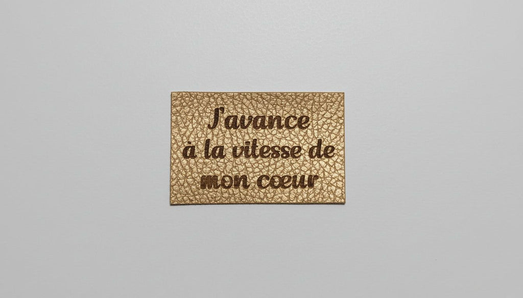 a rectangular, gold-colored label with the text "Savance a la vitesse de mon céeur" printed on it.