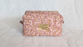 A pink and white floral patterned bag with a gold-colored tag that says "je parle la language des etétoires".