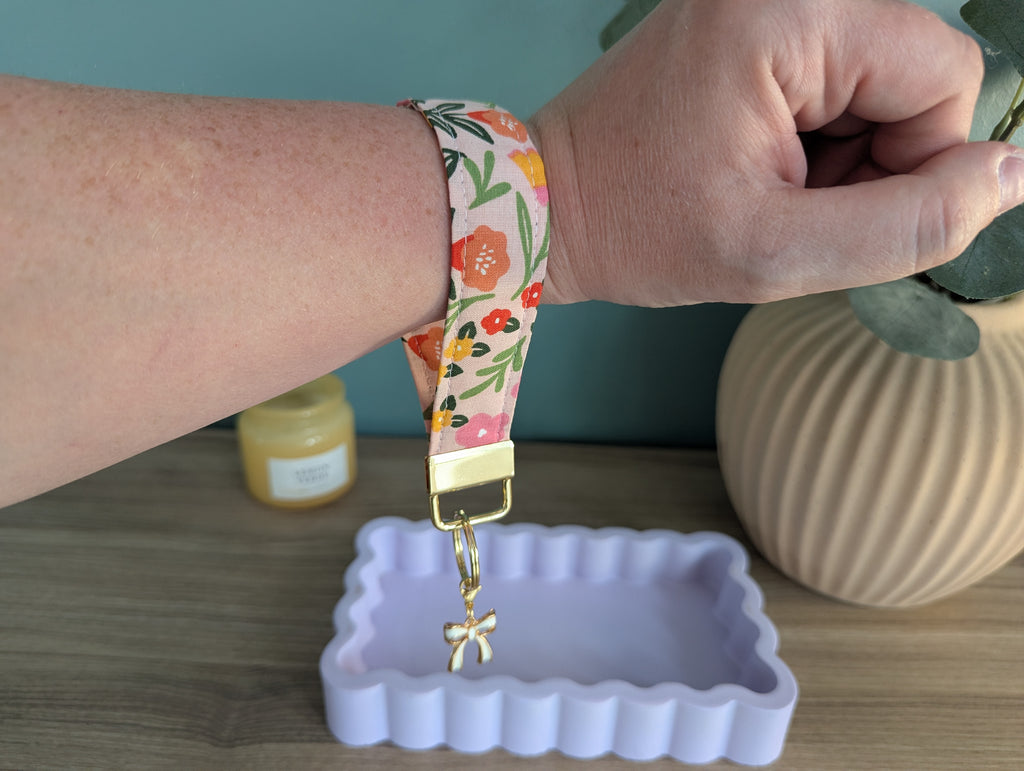 A person's wrist wearing a colorful floral-patterned watch band, with a small white tray or container in the foreground.