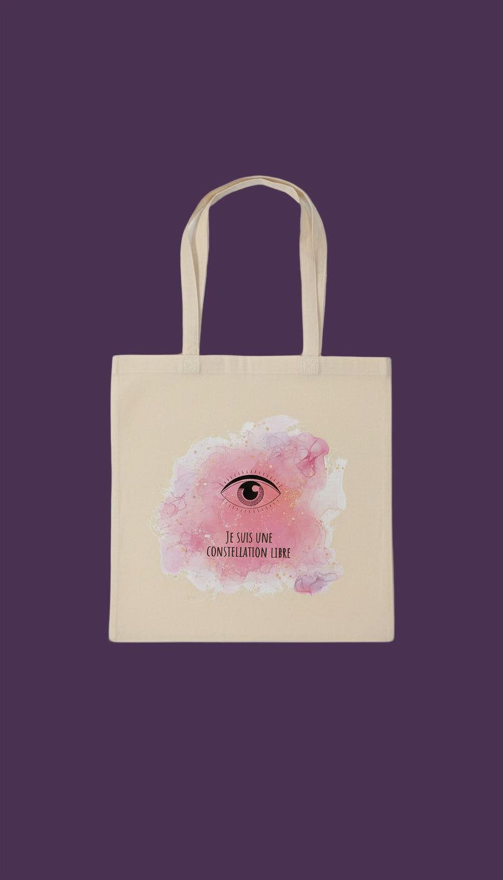 A beige tote bag with a pink and white watercolor design featuring an eye and the text "Je suis lune constellatione libre" (I am the constellation free).