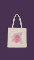 A beige tote bag with a pink watercolor design featuring a lotus flower and the text "Je suis monde propre refuge" (I am the world).