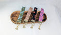 A wooden tray displaying four colorful keychains with different floral and geometric patterns.