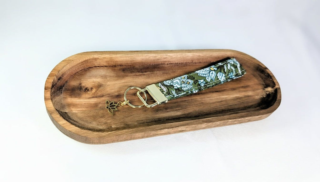 A wooden tray with a keychain featuring a floral pattern on it.