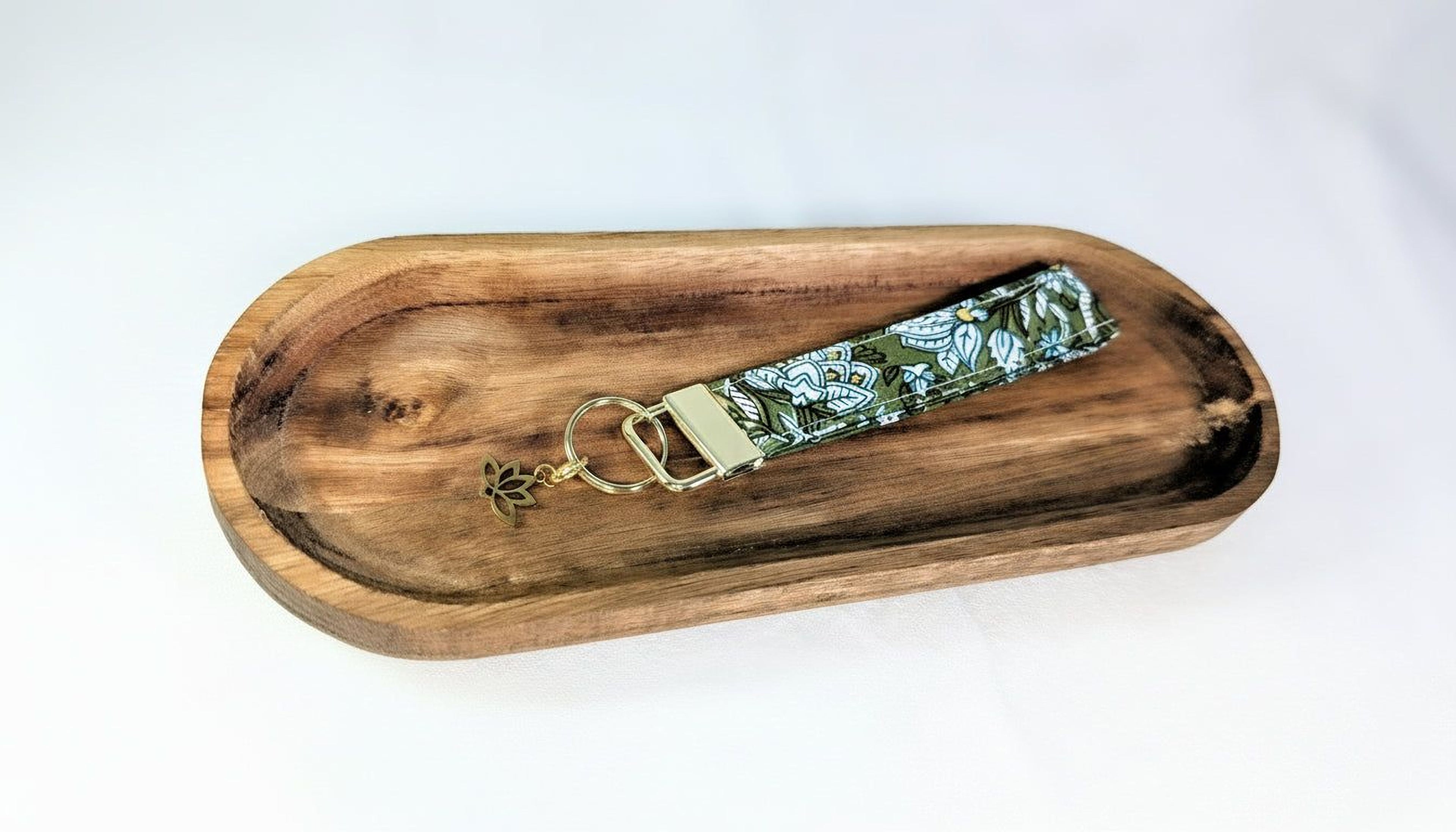 A wooden tray with a keychain featuring a floral pattern on it.