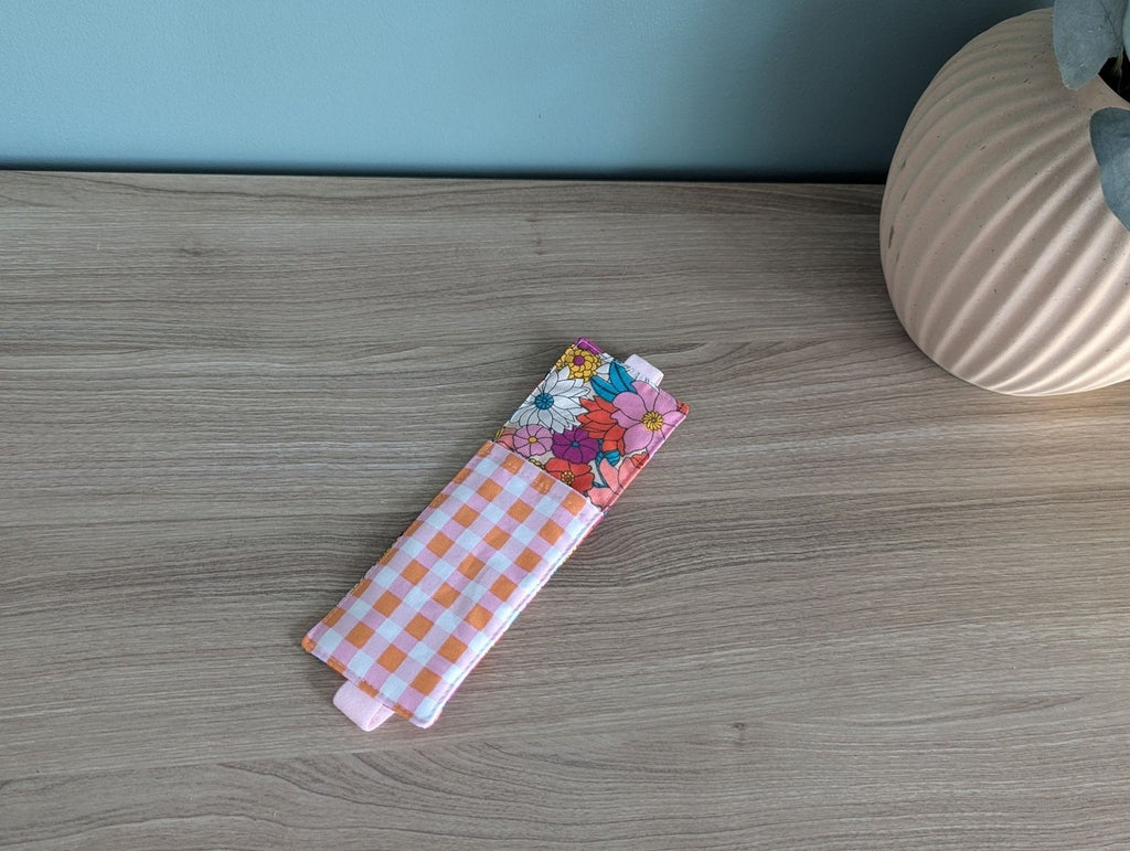 A colorful floral patterned object, possibly a bag or accessory, is placed on a wooden surface next to a vase.