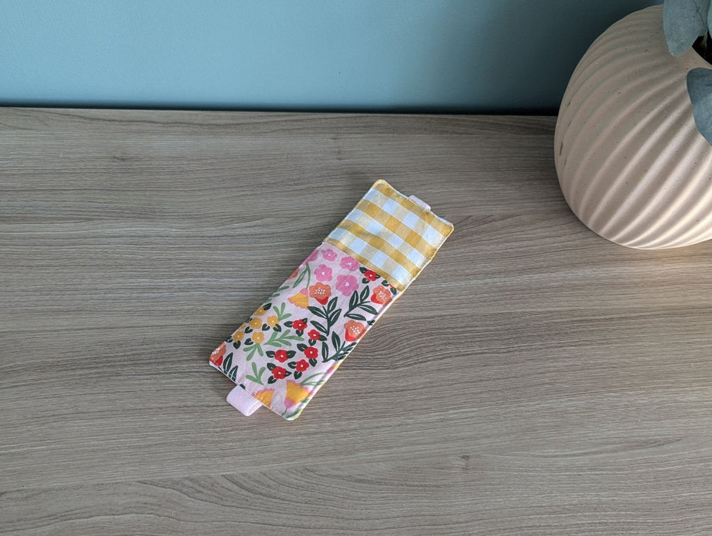 A colorful, patterned fabric item, possibly a bag or accessory, is placed on a wooden surface next to a vase.